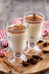 Eggnog with Cinnamon and Christmas Decorations on wooden table