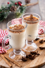 Eggnog with Cinnamon and Christmas Decorations on wooden table
