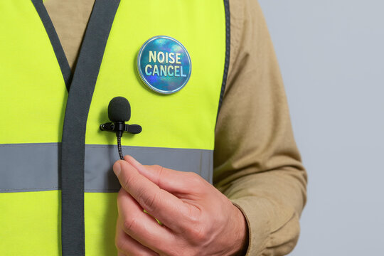 Noise cancel button on safety vest with microphone held by hand for emergency communication technology