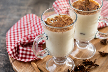 Eggnog with Cinnamon and Christmas Decorations on wooden table