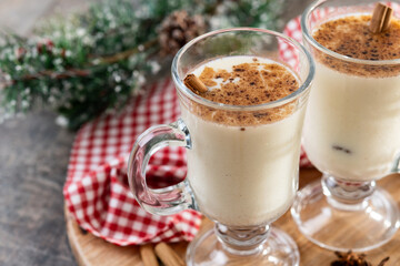 Eggnog with Cinnamon and Christmas Decorations on wooden table. Copy space