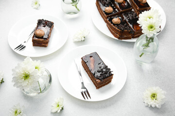Delicious chocolate cakes with cream and flowers on white plates with forks