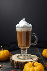 Warm spiced drink with whipped cream and mini pumpkins on dark backdrop