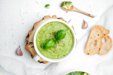 Green vegetable soup with basil and bread slice on a light background