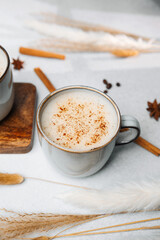 Creamy latte in a mug with cinnamon topping and soft natural elements