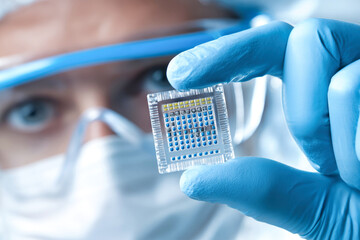 Engineer holding a microchip in clean room during technology development project