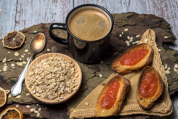 Rustic and healthy breakfast flat laybowl of raw oats, coffee, and toasted bread slices on a wood and fabric background. Cozy, natural, and perfect for morning energy concepts