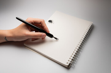 Calligraphy training. A fountain pen in someone's hands, stained with ink. Ink blot, pen on a white background, close-up