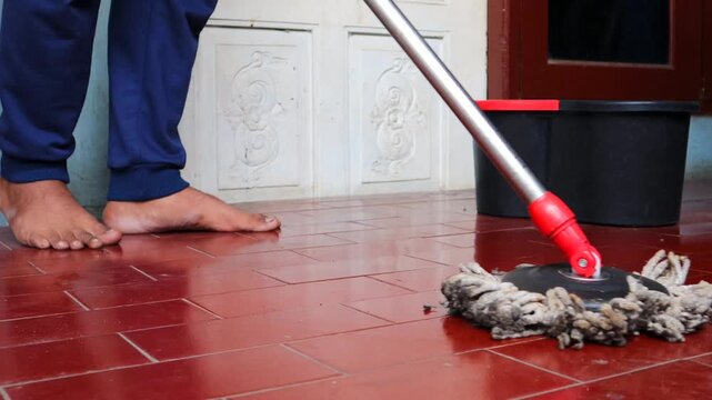 Asian man mops the floor indoors, cleaning her outdoor front home with a mop and rag. Maintaining a clean home.