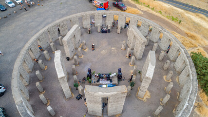 Aerial view of the Stonehenge Memorial radiates ancient mystique under the summer sun, its weathered stones contrasting against the golden, grassy surroundings, Goldendale, Washington, United States.