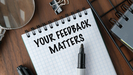 A notebook with a pen on it that says "Your feedback matters"