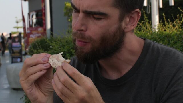 Close-Up Portrait of Man Eating Chicken Piece Outdoors