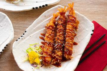 Prawn tempura on white dish, crunchy Japanese deep fried seafood served with salad.