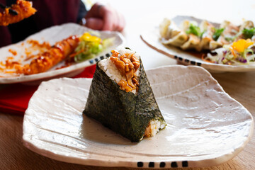 Onigiri, rice balls with teriyaki chicken in nori seaweed on a white plate.