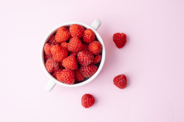 Top view of raspberries in a bowl  on pink background for diet blog or fruit branding concept