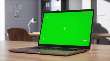 Modern Laptop with Green Screen Display on a Wooden Desk in a Contemporary Office Environment Ideal for Digital Content and Technology Mockups.