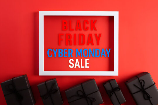 Top view of Cyber Monday Sale text in white picture frame with black gift box on red background, perfect for online shopping promotions