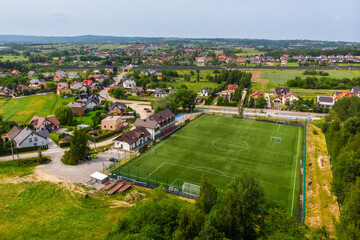 Aerial view of a village with a sports field and surrounding houses in Małopolska, Poland
