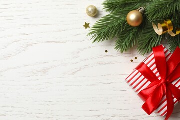 Christmas holiday concept. Fir branches, a gift, and glittering ornaments on white background