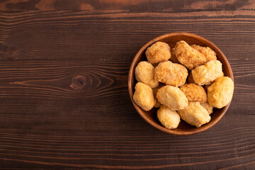 Fried crispy Chicken Nuggets on brown wooden. top view, copy space