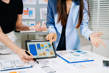 UX developer and ui designer brainstorming about mobile app interface wireframe design with customer breif and color code at modern office.