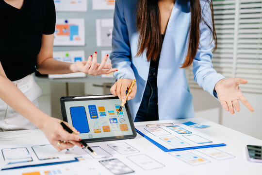  UX developer and ui designer brainstorming about mobile app interface wireframe design with customer breif and color code at modern office.