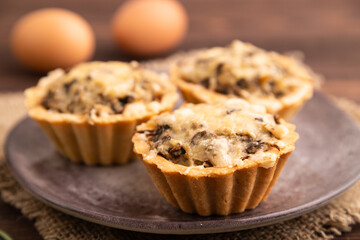 Tartlets with meat and cheese on brown wooden, linen textile. side view, close up, selective focus