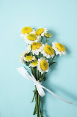 chrysanthemums bouquet tied with white ribbon on mint aqua background, upright composition. Elegant, fresh, ideal for eco branding, wedding, invitations, skincare, natural products, wellness. Top view