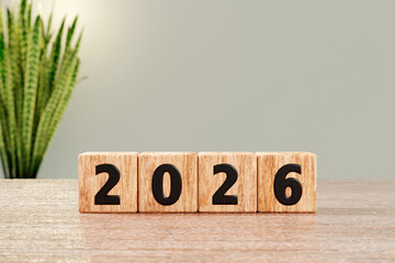 Wooden blocks show 2026 on desk with soft plant background