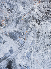 Macro shot of ice crystals and frost on glass: delicate frozen patterns shimmering in cool light. Abstract winter texture with geometric shapes, perfect for backgrounds, design, and seasonal projects.