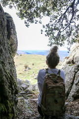 Blonde woman with a bun looking at the mountains after walking along the paths accompanied by her dog