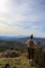 Blonde woman with a bun looking at the mountains after walking along the paths accompanied by her dog