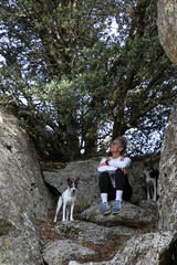 Blonde woman with a bun looking at the mountains after walking along the paths accompanied by her dog