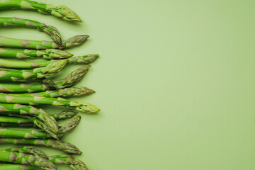 Side border of asparagus spears on green background with copy space