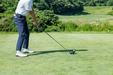 緑が綺麗なゴルフ場でプレイする人
