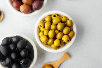 Variety of olives in bowls  on gray background, green olives, black and kalamata olives.