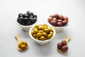 Variety of olives in bowls  on gray background, green olives, black and kalamata olives.