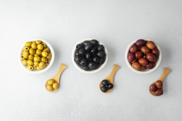 Assortment of green,  black and  kalamata  olives in bowls with wooden spoons