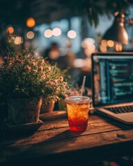 Cozy workspace featuring a drink, laptop, and plant in an ambient setting.