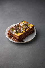 Piece of cake with pear jelly and chocolate flakes on white plate, grey background. Copy space