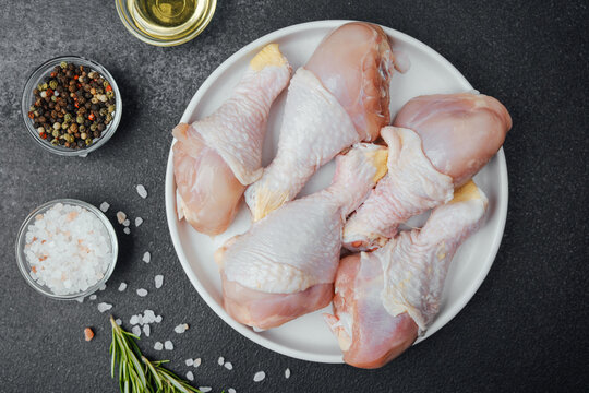 Chicken drumsticks raw with spices and herbs on white plate