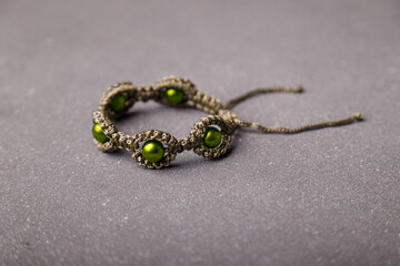 Green beaded bracelet from macrame yarn on grey background. Copy space