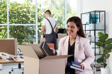 Moving day. Workers putting different belongings into cardboard boxes in office