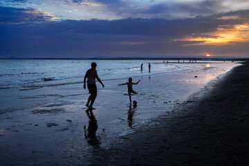 Father and child play football at sunset in Ayamonte, Spain