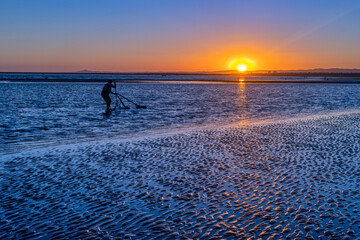 Shellfish harvester working at sunset in Isla Canela, Ayamonte