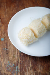 Pismaniye, cotton candy or dragons beard with vanilla taste on white plate, wooden background. Turkish dessert, light halva, candy floss. Copy space