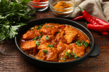 Chicken tikka masala with spices on wooden table, closeup