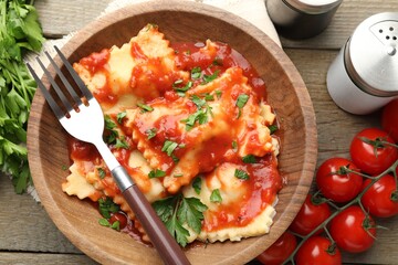 Delicious ravioli with tomato sauce and parsley served on wooden table, flat lay