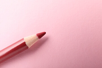 Red eye pencil on pink background, top view. Space for text