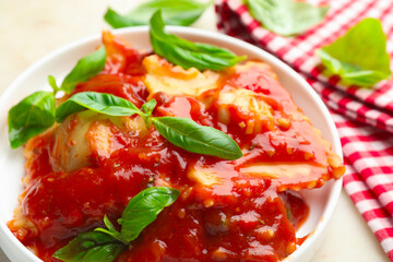 Delicious ravioli with tomato sauce and basil on white table, closeup